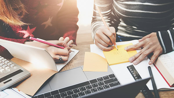 two people writing on paper